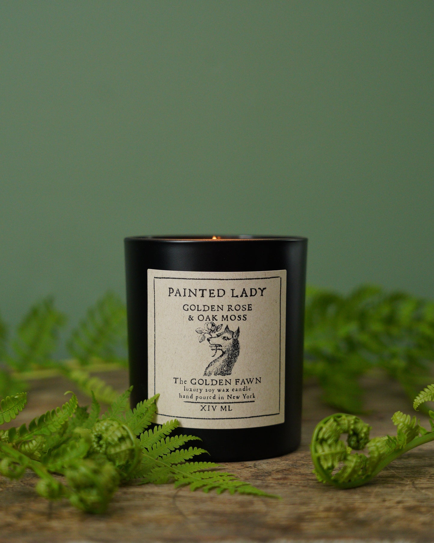 Candle with a label on a wooden surface with green foliage