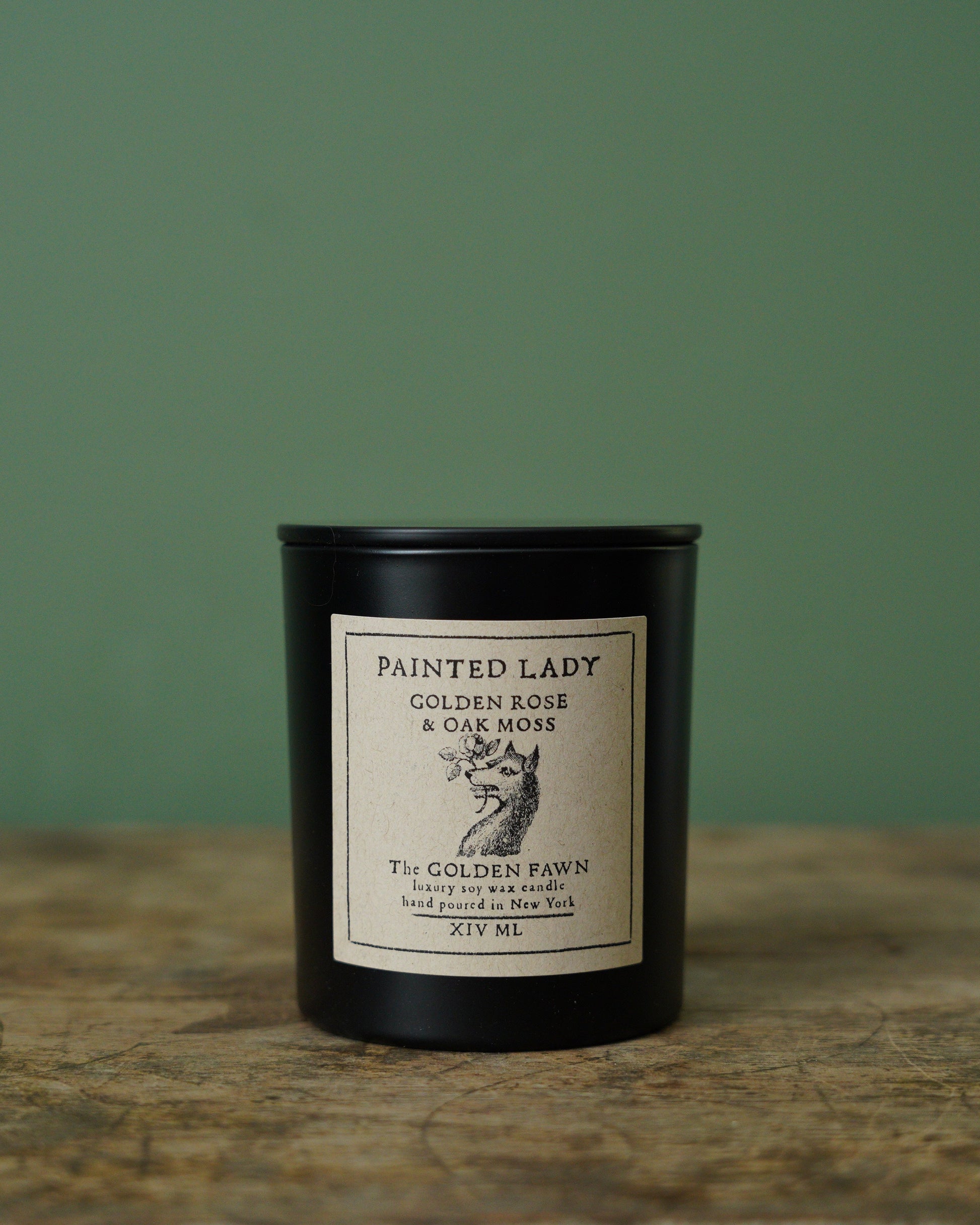 Black candle with a label on a wooden surface and green background