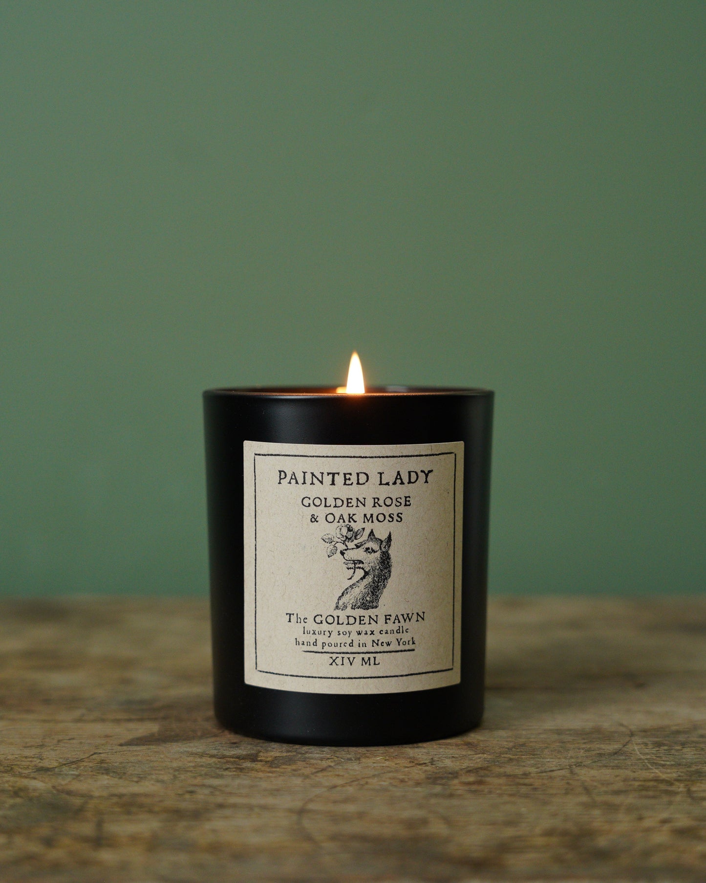 Candle with a label on a wooden surface and green background