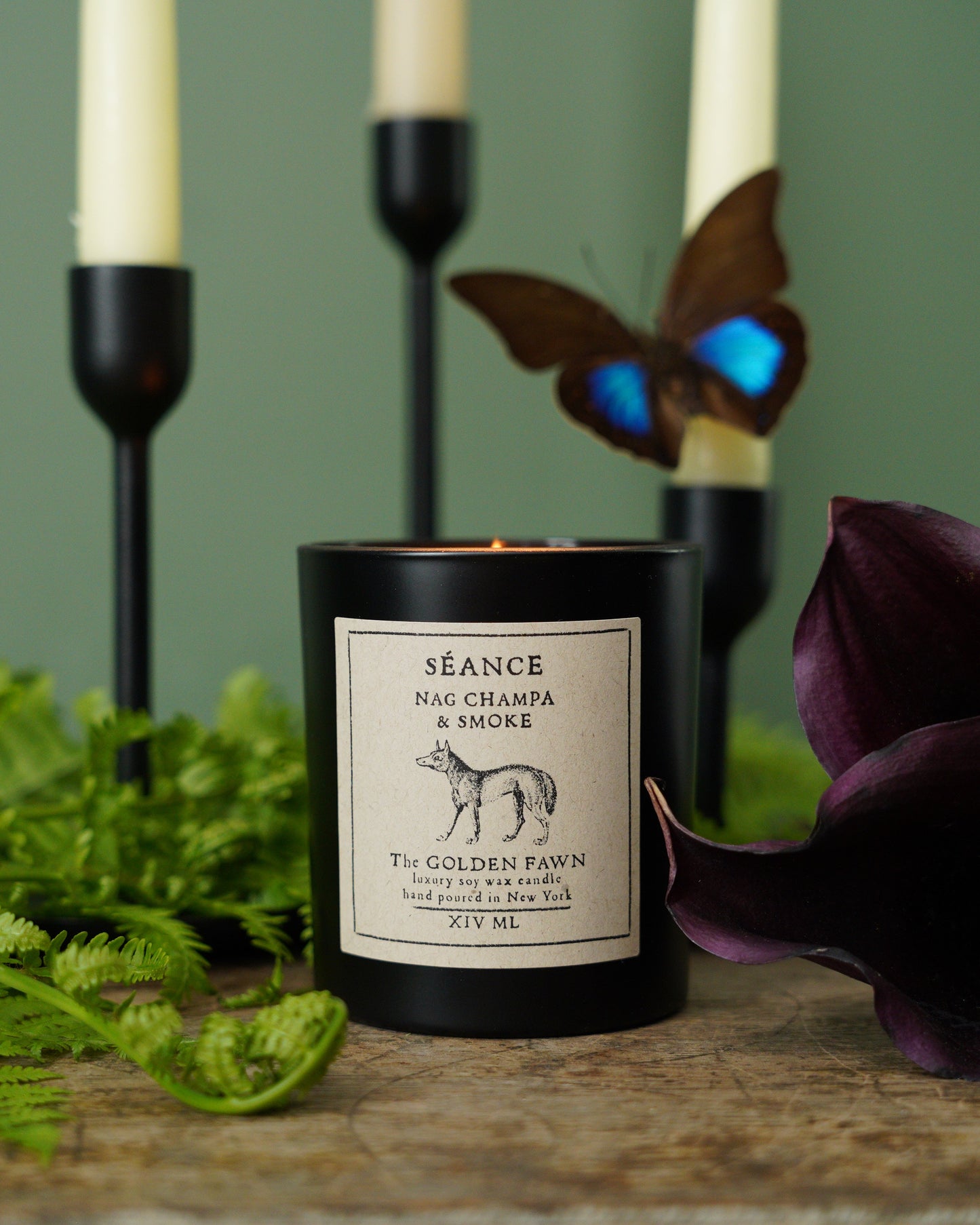 Candle with a butterfly and flower on a wooden surface
